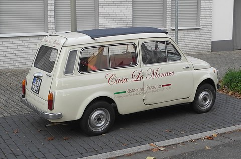 Cream small estate with Casa La Monaco lettering on its doors and a dark blue sunroof, parked on paving. Opens a larger view