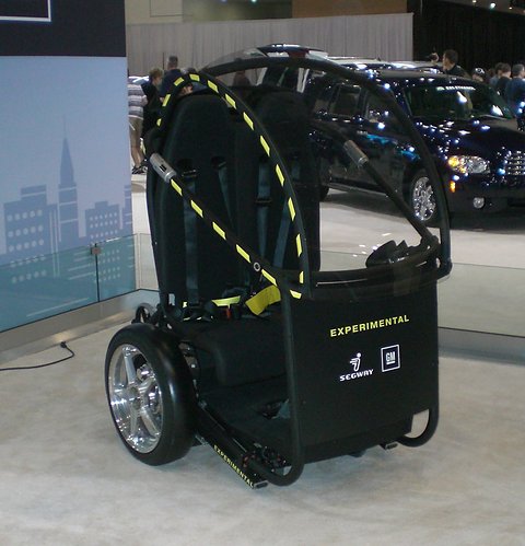 Black two-wheeled two-seat frame with a yellow-striped roll hoop and EXPERIMENTAL lettering on a carpet. Opens a larger view