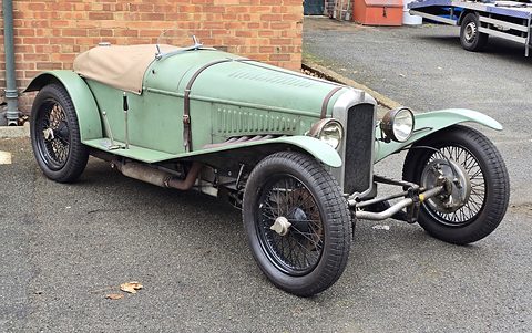 A long pale green two-seat sports car with a louvred bonnet, cycle wings, wire wheels and exposed exhaust pipes. Opens a larger view