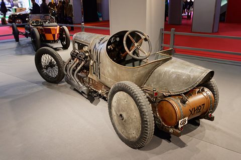 Rear quarter view of a bare-metal racing car with a copper tank on the tail and disc rear wheels. Opens a larger view