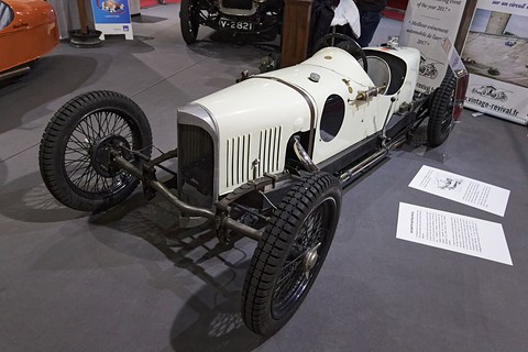 A white single-seat racing car with a louvred bonnet and black wire wheels on grey carpet. Opens a larger view