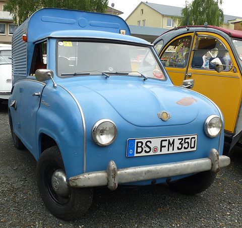 Blue saloon front joined to a tall ribbed metal box body, seen from the front left. Opens a larger view