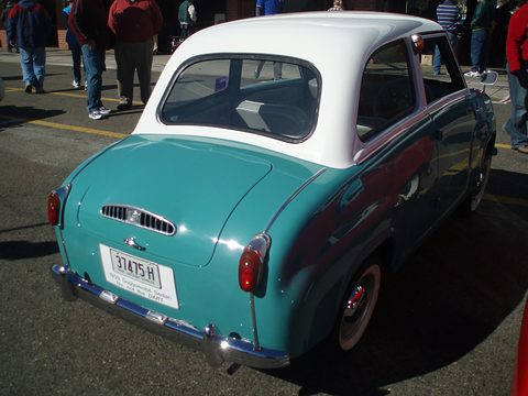 Back of a teal saloon with a white roof, louvred engine lid and a historic-vehicle number plate. Opens a larger view