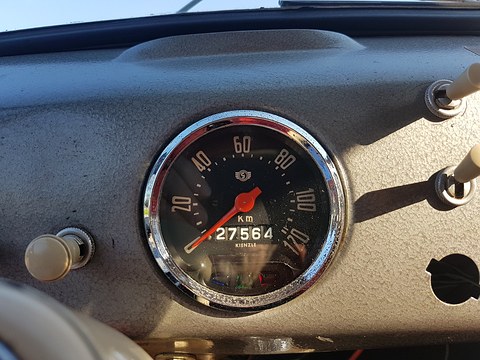 Round speedometer with an orange needle and odometer set in a grey crackle-finish dashboard. Opens a larger view