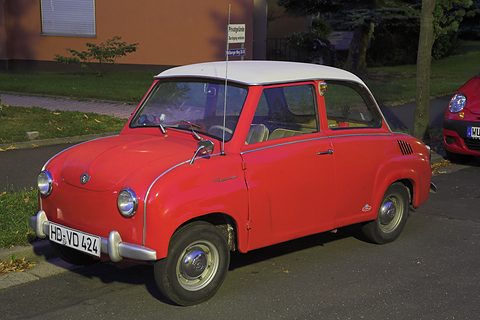 Red saloon with a white roof parked on a road verge, seen from the front left. Opens a larger view