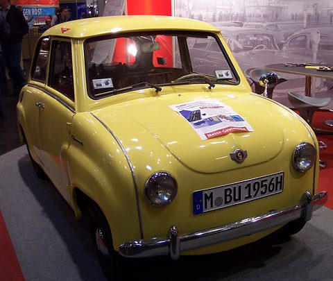 Yellow saloon seen from the front with a prize-draw leaflet on the bonnet and a Munich number plate. Opens a larger view