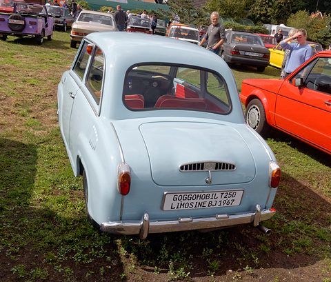 Back of a pale blue saloon with louvred engine lid and a sign on the bumper naming the model. Opens a larger view