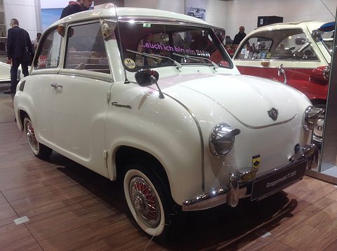 White saloon with a cream roof and whitewall tyres on a wooden floor, seen from the front right. Opens a larger view