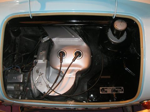 Engine bay framed by pale blue bodywork, silver fan cowling with two spark-plug leads and an air filter