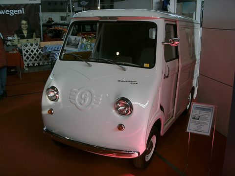 White panel van on a red show carpet, seen from the front left. Opens a larger view