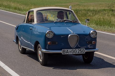 Blue coupé with a cream roof driving towards the camera on a rural road