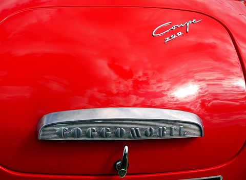 Close-up of a chrome handle with Goggomobil lettering and a Coupé 250 script on red paint. Opens a larger view