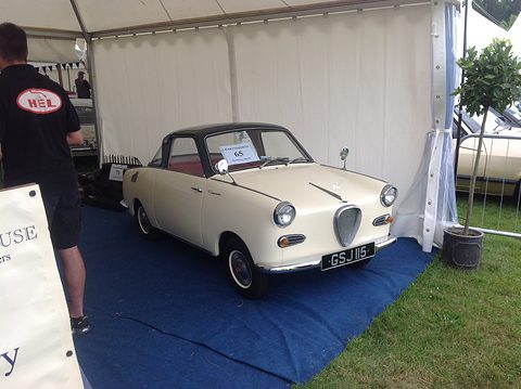 Cream coupé with a black roof on a blue carpet inside a white marquee. Opens a larger view