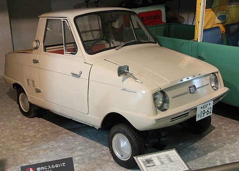 Cream pickup with a chrome nose strip, a wing mirror and a Japanese number plate, on a stone floor. Opens a larger view