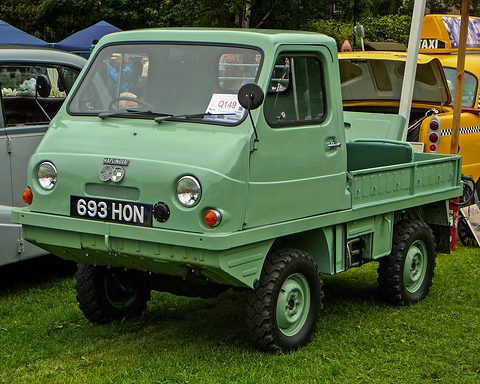 Light green small truck with a rounded plastic cab and a British plate parked on grass.