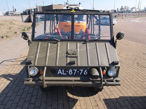 Front of a small olive 4x4 with a ribbed nose, round headlamps and a fold-down windscreen. Opens a larger view