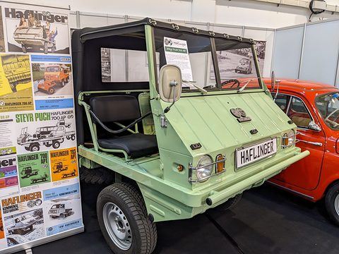 Pale green small open 4x4 with a Haflinger plate beside a display of old brochure covers. Opens a larger view