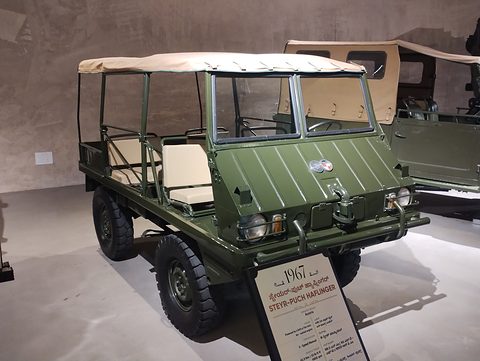 Olive small 4x4 with a cream canopy and bench seats, a 1967 museum label in front. Opens a larger view