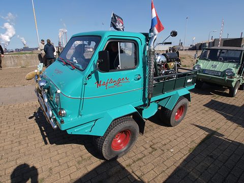 Turquoise small truck with a rounded cab, script on the door, chrome exhaust stack and red wheels. Opens a larger view