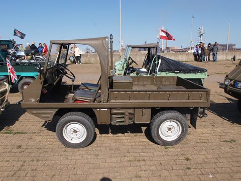 Side view of a small olive 4x4 with a short cab top and a flat load platform behind. Opens a larger view