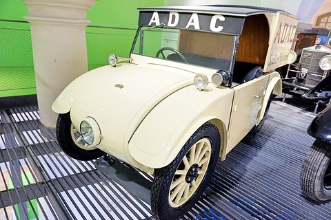 A cream open car with an ADAC sign on a frame above its cab and a box body, on a slatted floor. Opens a larger view