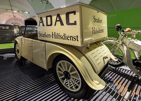 Rear three-quarter view of a cream car with a tall lettered box body and a louvred rear wing. Opens a larger view