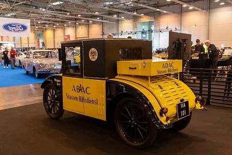 Rear three-quarter view of a yellow road-patrol car with a lettered tool box on its louvred tail. Opens a larger view