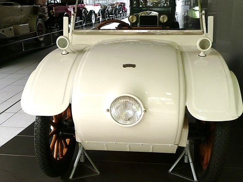 Front view of a cream rounded bonnet with a single round headlamp at its centre, flanked by wings. Opens a larger view