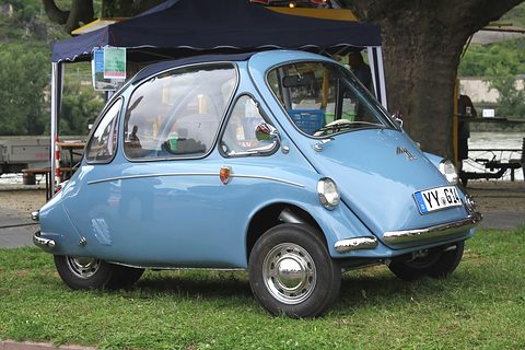 Pale blue bubble car on grass under a gazebo, a German number plate on its nose. Opens a larger view
