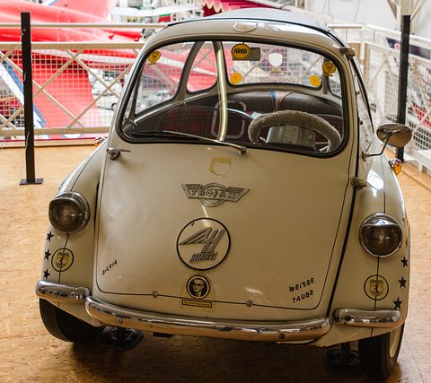 Cream bubble car head-on with Trojan and winged Heinkel badges, stars and stickers on its nose. Opens a larger view