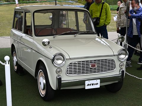 Cream small bonneted estate van with a chrome grille on artificial turf, visitors behind a rope. Opens a larger view