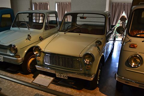 Cream small bonneted pick-up with a chrome grille and round headlamps beside a pale blue one. Opens a larger view
