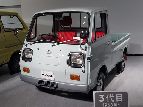White small cab-over pick-up with square headlamps and red seats beside a ‘3rd generation’ sign. Opens a larger view