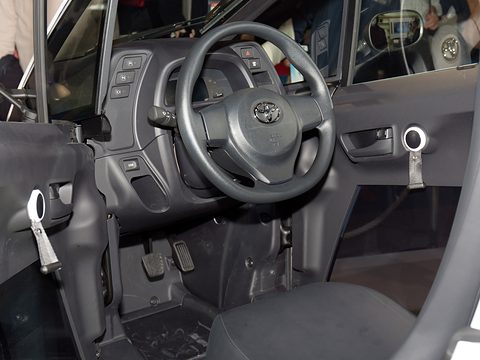 Grey dashboard with a Toyota steering wheel, small switches, a door strap and the narrow footwell. Opens a larger view