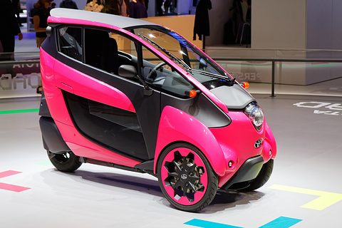 Pink and black narrow three-wheeler on a white stand marked with coloured arrows. Opens a larger view