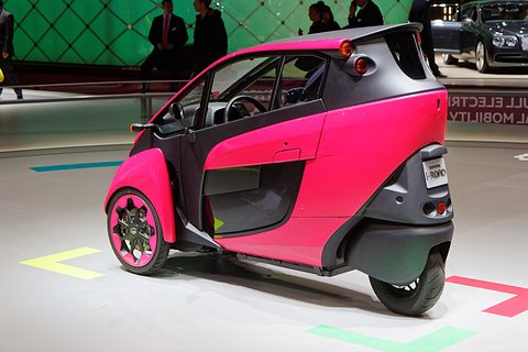Rear of a pink and black narrow three-wheeler with a single small rear wheel, on a white stand. Opens a larger view