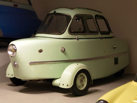 Pale green three-wheeler with a single headlamp in its rounded nose, separate front wings and a glazed domed canopy. Opens a larger view