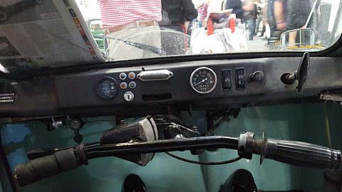 Driver’s view of motorcycle-style handlebars in front of a simple dash with one round dial.