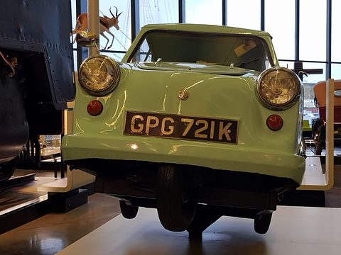 Low front view of a mint-green three-wheeler on a plinth showing the single front wheel. Opens a larger view
