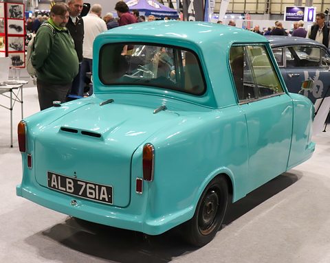 Rear of a turquoise single-seat three-wheeler with a louvred engine lid and twin tail lamps. Opens a larger view