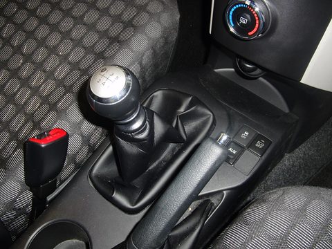 Chrome-topped gear knob with a six-speed pattern, a leather gaiter, a seat-belt buckle and patterned seat fabric. Opens a larger view