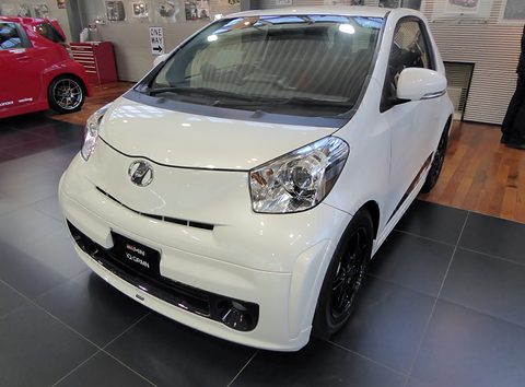 White city car with black wheels and a GRMN plate on a dark showroom floor. Opens a larger view