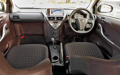 Two checked front seats, a steering wheel on the right and a dashboard that sweeps back on the passenger side to a navigation screen.
