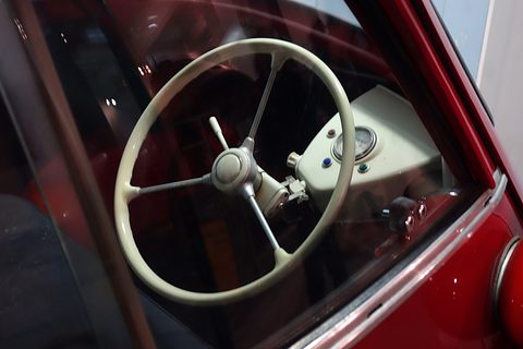 Cream steering wheel and column seen through a car window. Opens a larger view