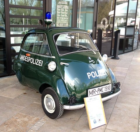 Dark green bubble car with Landespolizei lettering and a blue beacon, an information board beside it. Opens a larger view