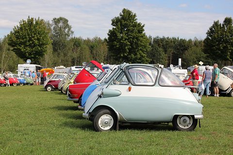 Row of bubble cars of many colours parked on grass, a pale blue one in front. Opens a larger view