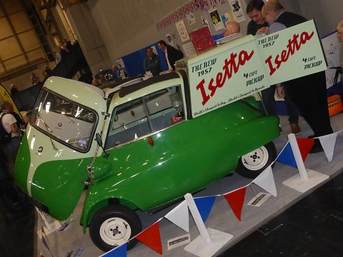 Green bubble car with a flat load bed and a period-style sign announcing the Isetta pick-up. Opens a larger view