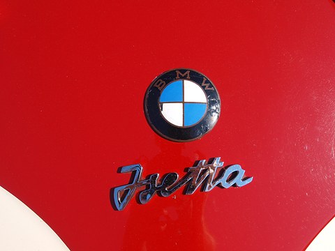 BMW roundel above a chrome Isetta script on red paint. Opens a larger view