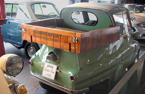 Green bubble car with a wooden box on the back lettered Krimpenfort, in a museum. Opens a larger view