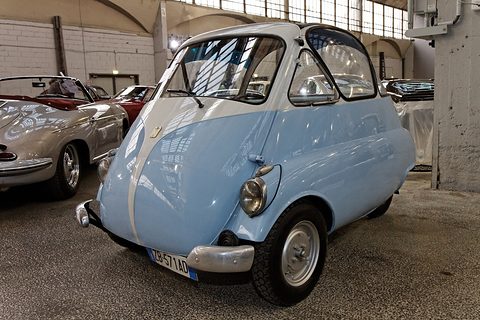 Low view of a pale blue bubble car’s nose, the whole front a door with a white stripe and flush handle. Opens a larger view